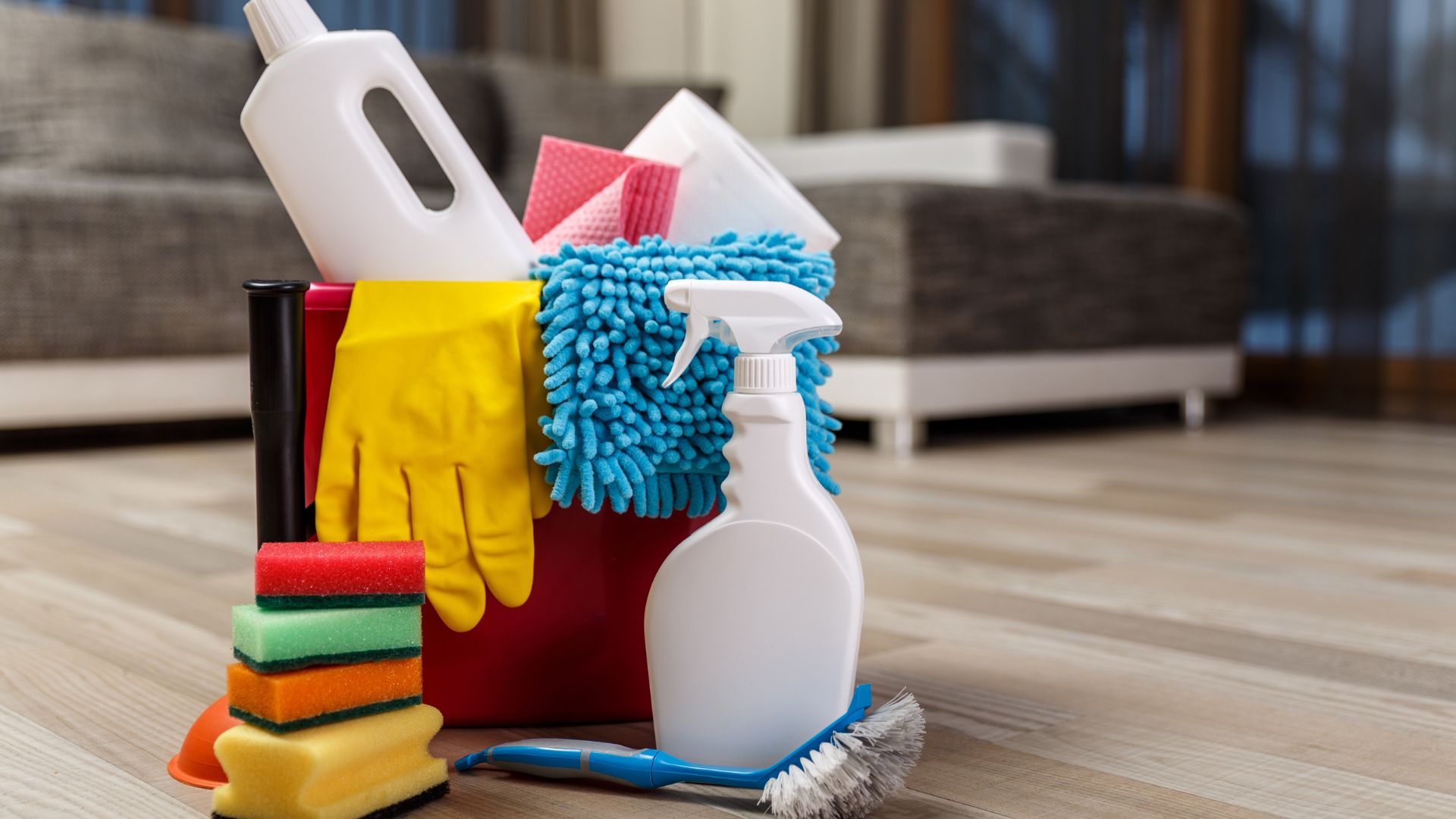 Colorful cleaning supplies and tools arranged on wooden floor