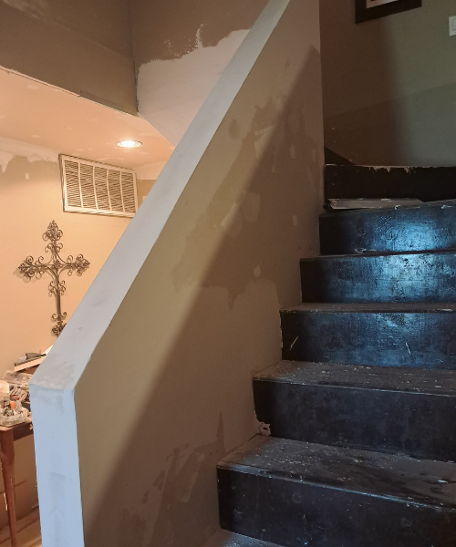 Dark stone staircase with white wall and decorative cross in background